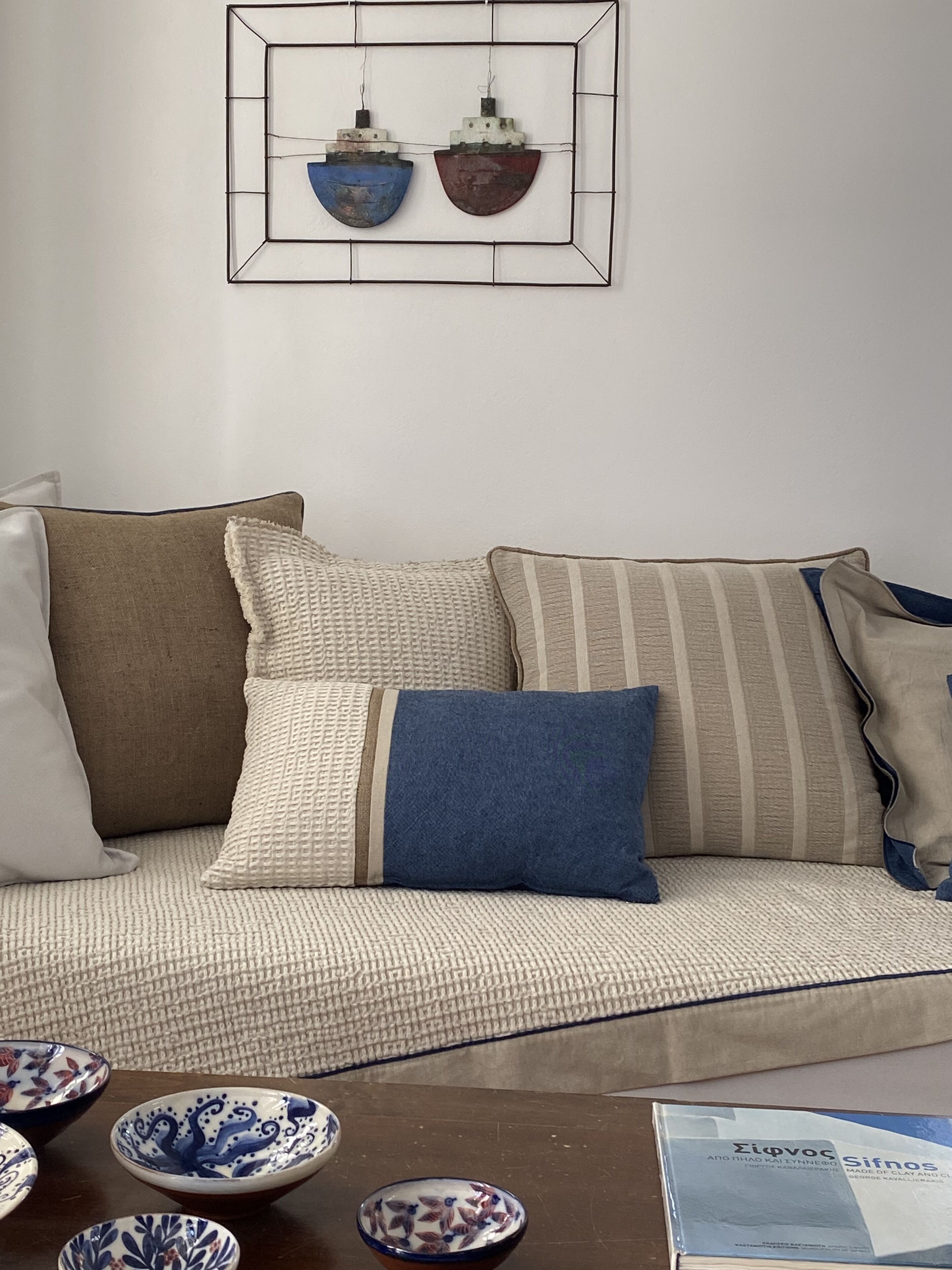A living room with a sofa, cushions, and decorative bowls on a table.