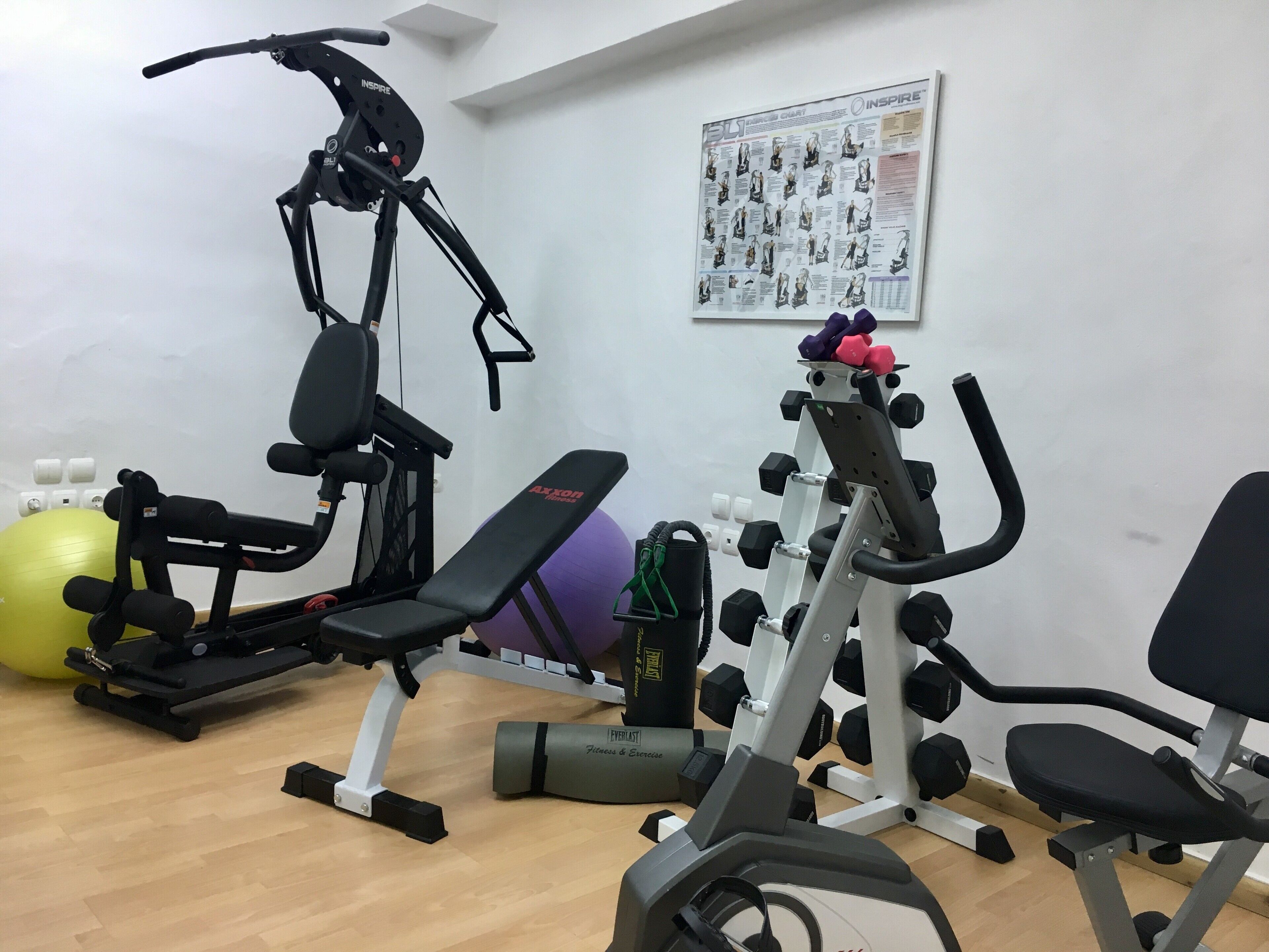 A gym with exercise equipment including a stationary bike, a bench, and a weight bench.