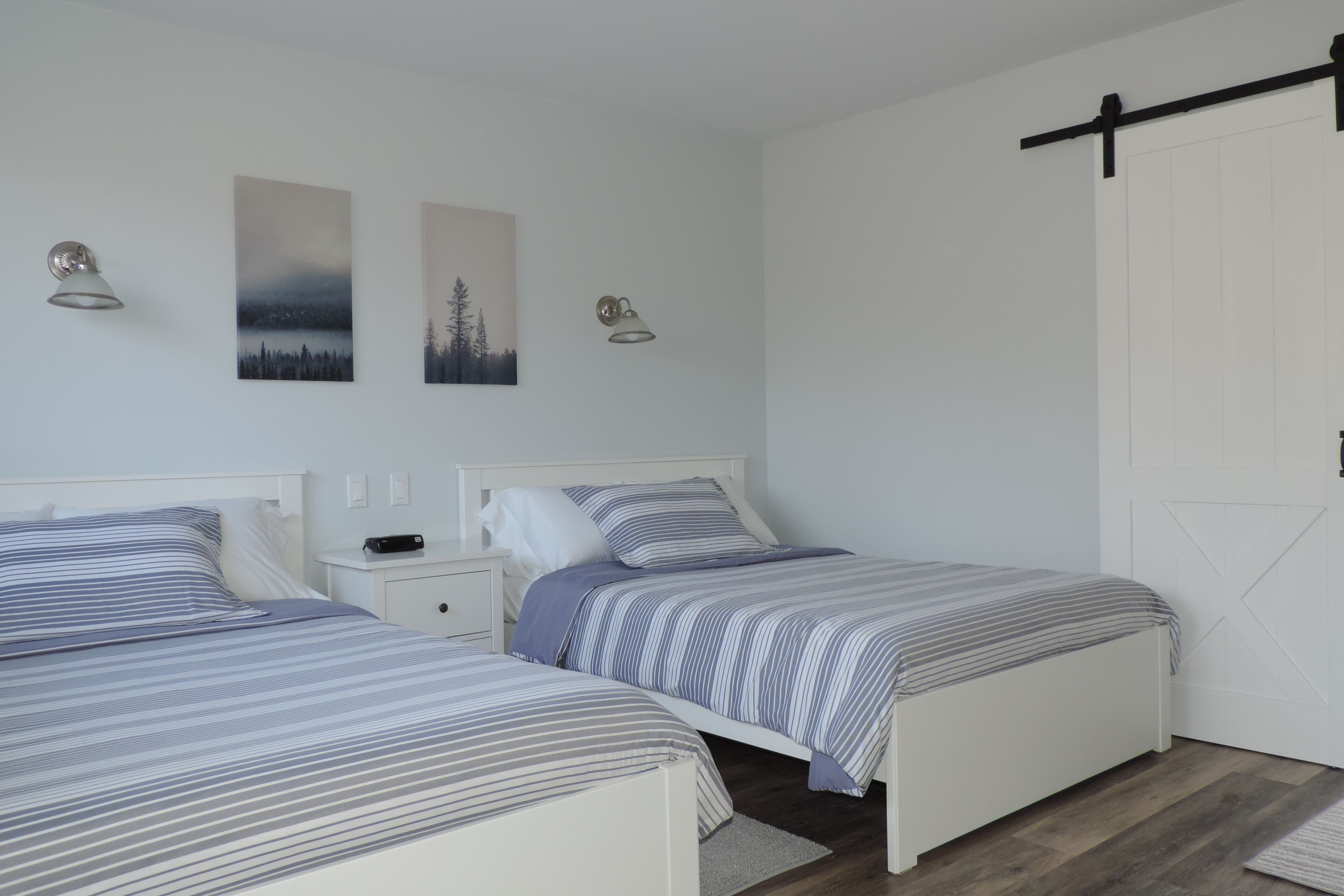 Een slaapkamer met twee bedden, een witte inloopkast en twee wandlampen.