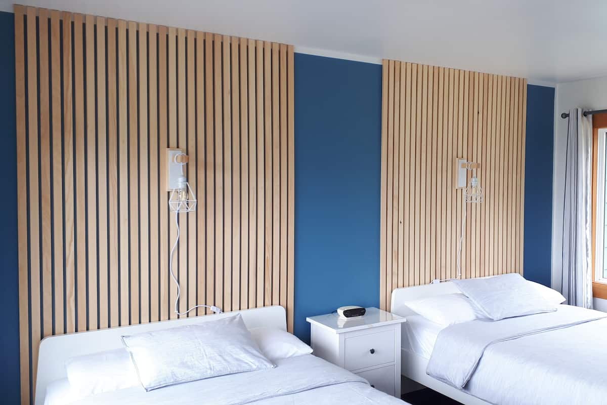 A hotel room with two beds, a nightstand, and a wooden panel wall.