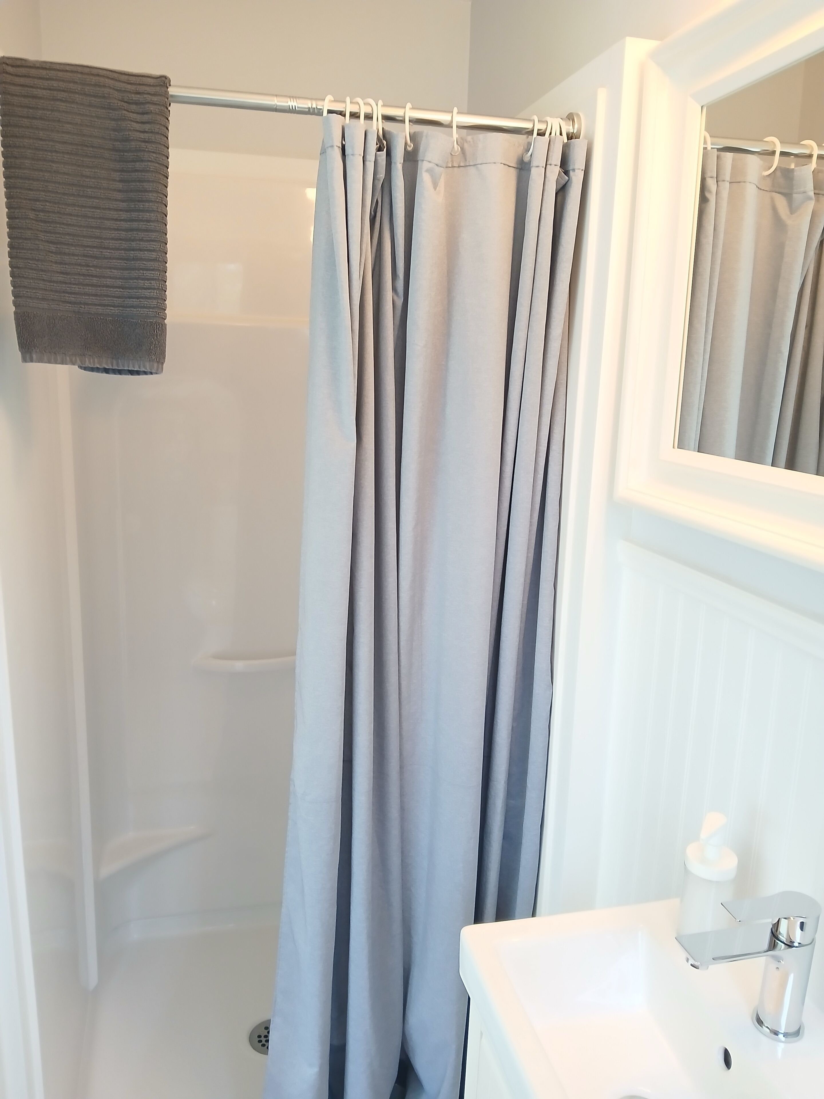 A bathroom with a shower curtain, a sink, and a mirror.