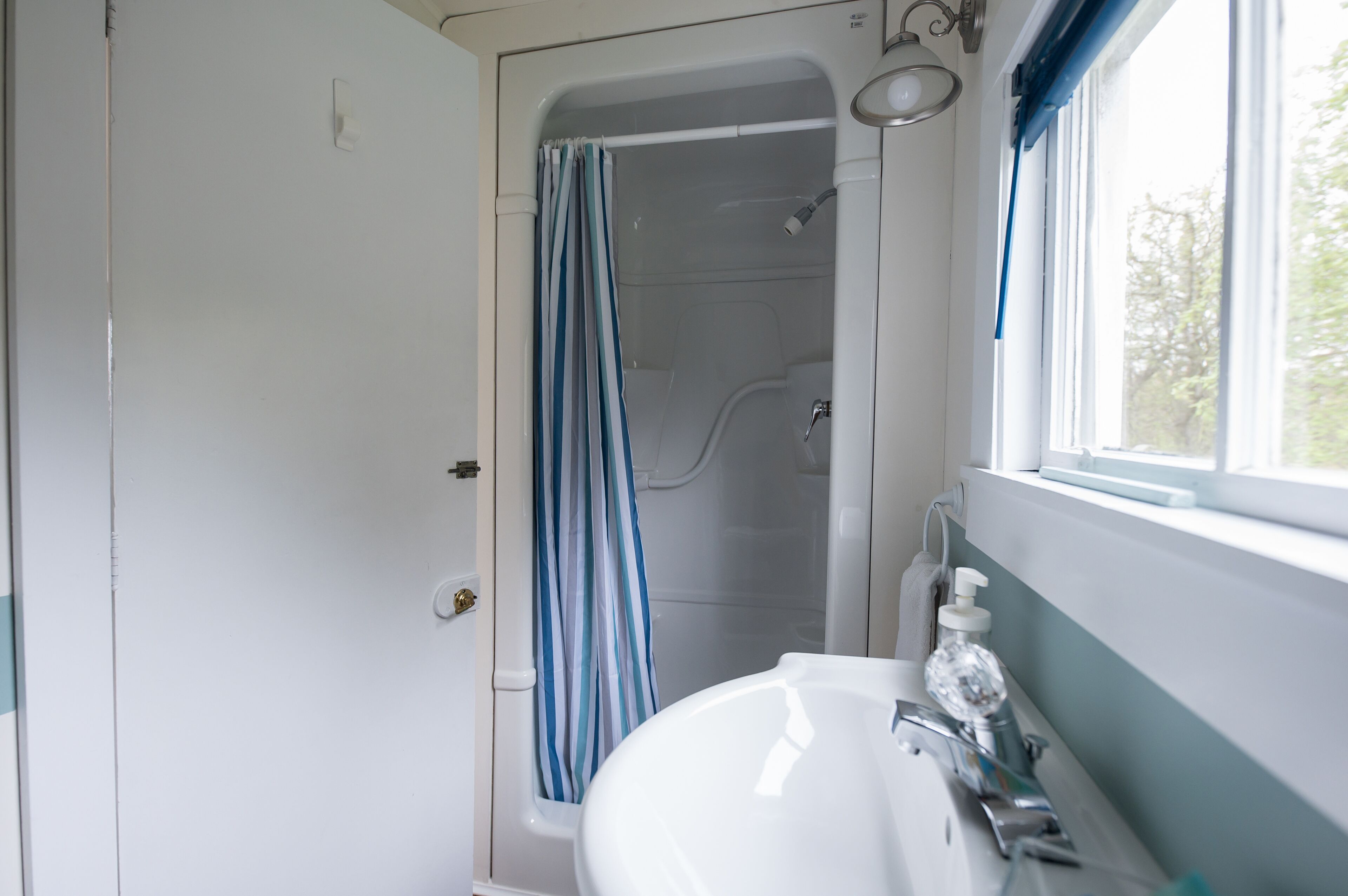 Un baño con ducha, lavamanos y ventana.