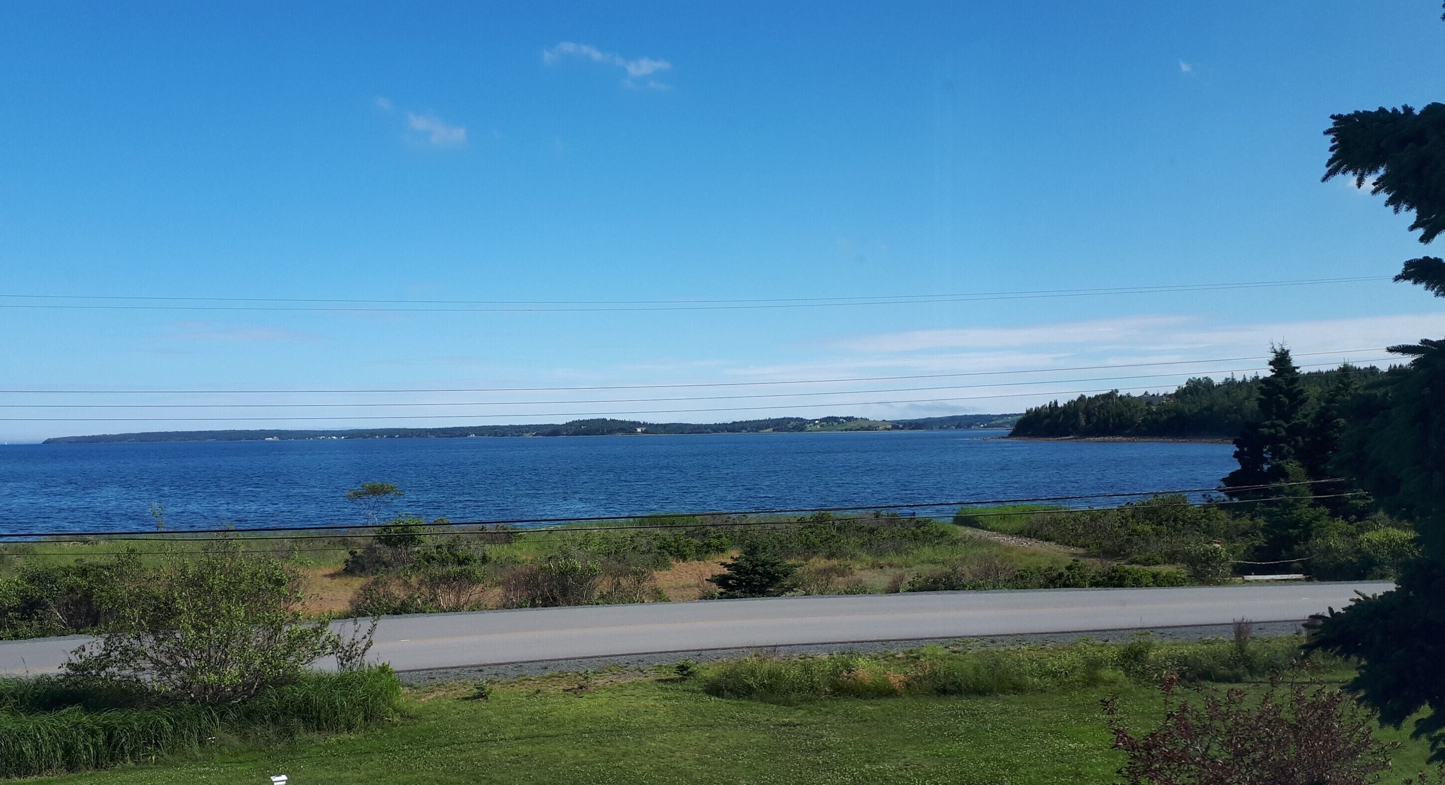 A coastal road with a view of the sea and distant land.