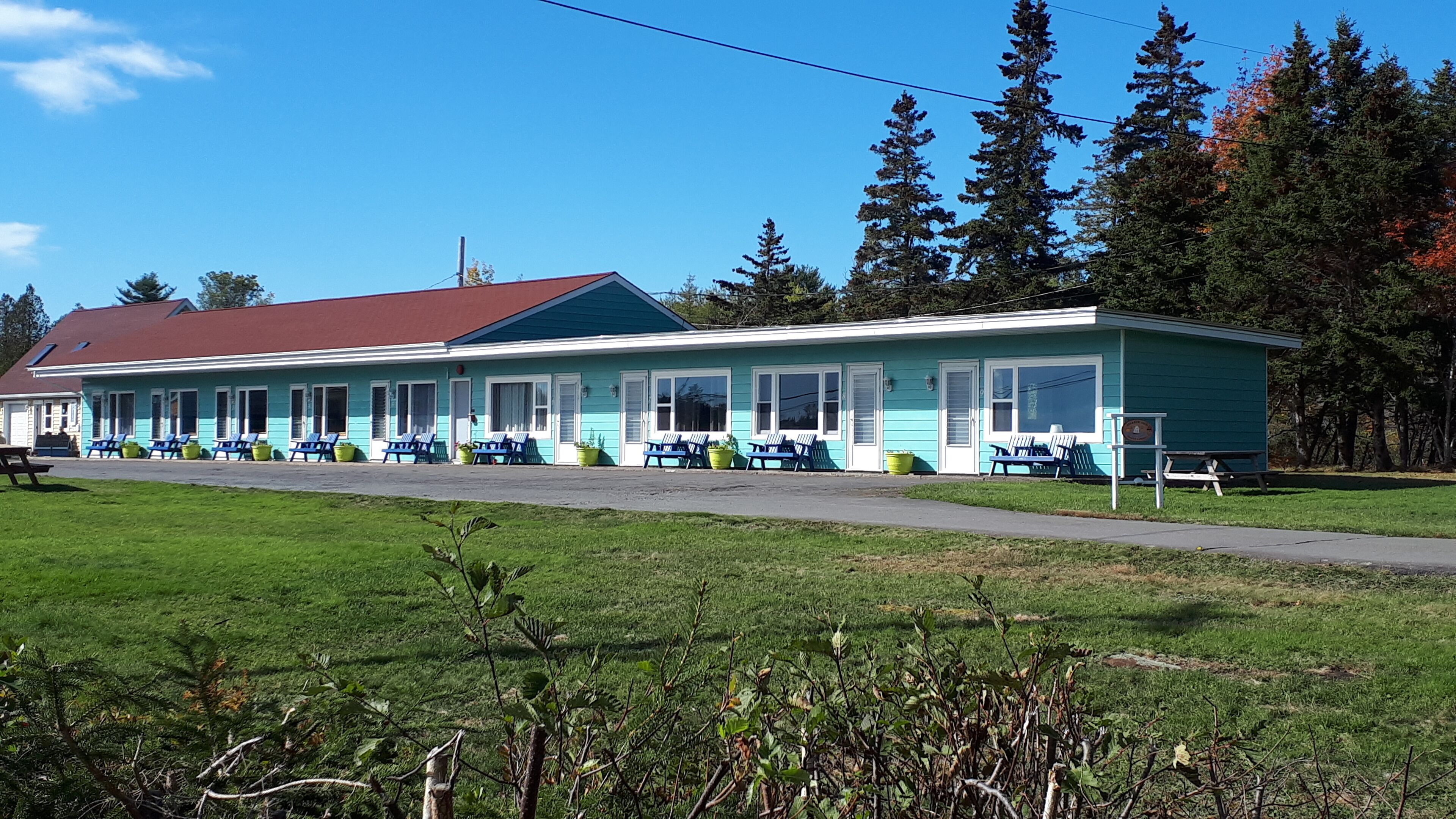 Um motel com uma fileira de quartos térreos, cada um com janela e porta.