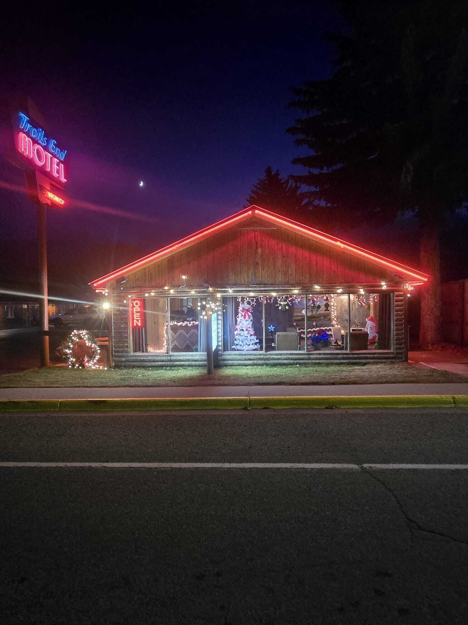 Ein Motel mit leuchtendem Neonzeichen, rotem Dach und Weihnachtsdekorationen.