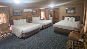 Quarto de hotel com duas camas, um sofá, uma cadeira e uma televisão.