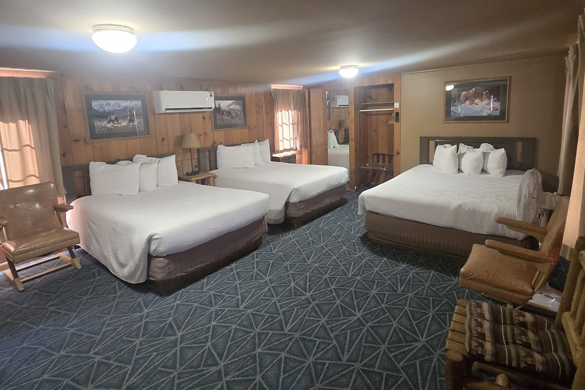 A hotel room with two beds, a sofa, a chair, and a TV.