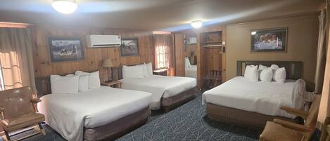 A hotel room with two beds, a sofa, a chair, and a TV.
