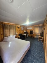 Habitación de hotel con una cama grande, un escritorio con una silla, un televisor y una mesita.