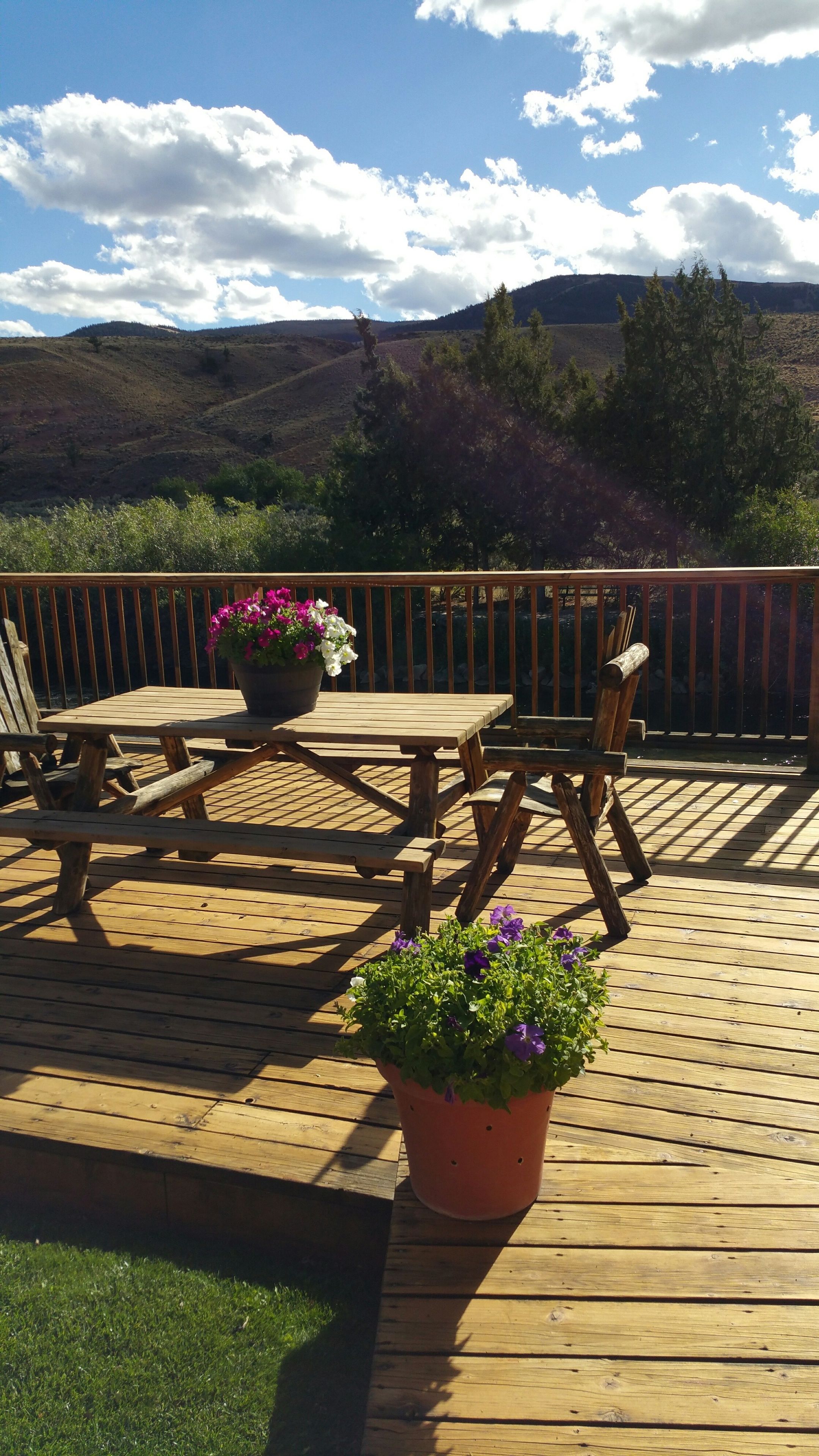 A wooden deck with a table and chairs, surrounded by a metal railing.