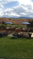 Terraza con asientos exteriores y sombrillas azules, con vistas a un paisaje montañoso.