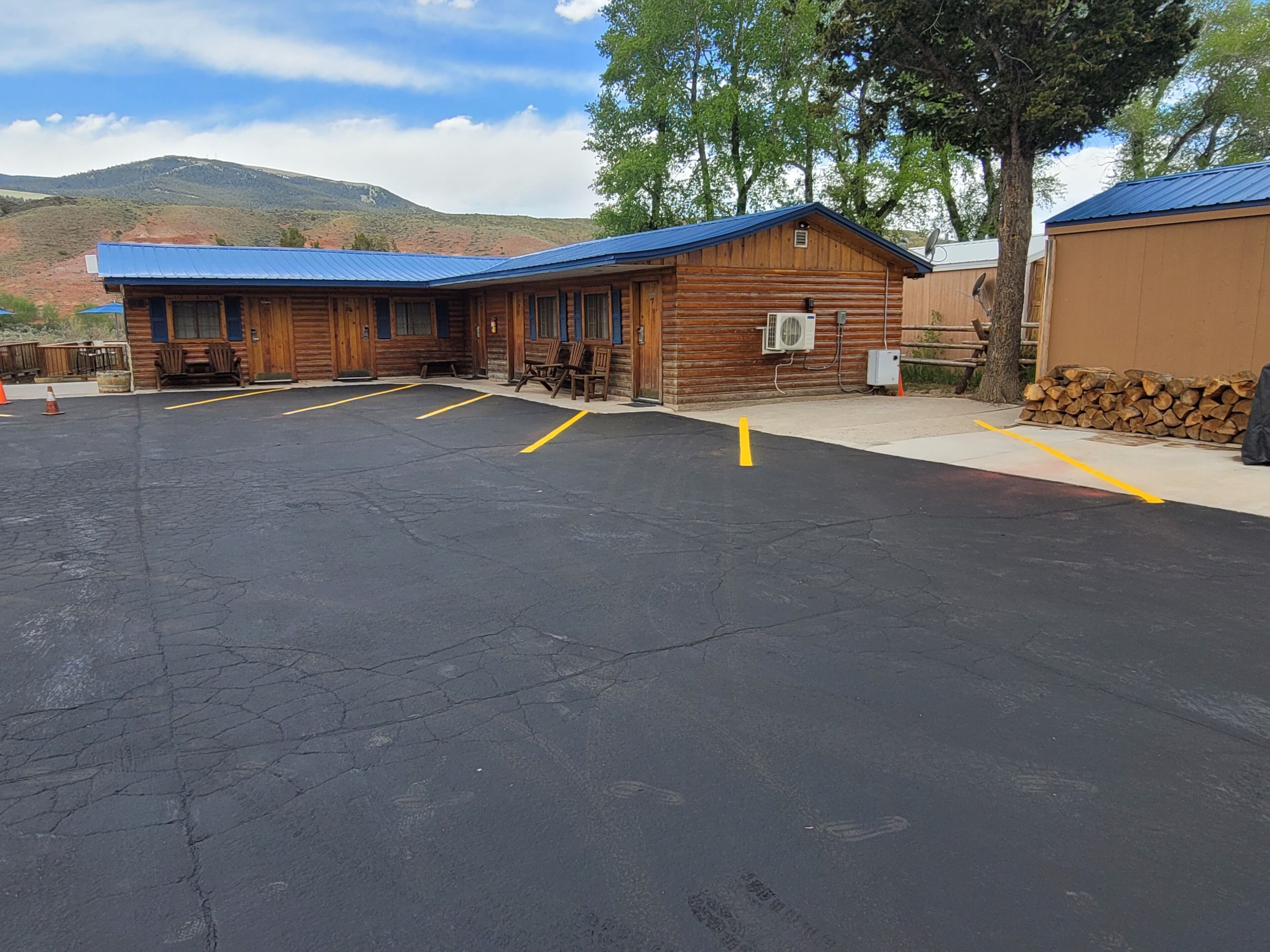 A building with a blue roof, a parking lot with yellow lines, and a mountain in the background.