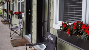 A building with a porch, outdoor seating, and flower boxes. - Studiotel Bromont (Bromont)