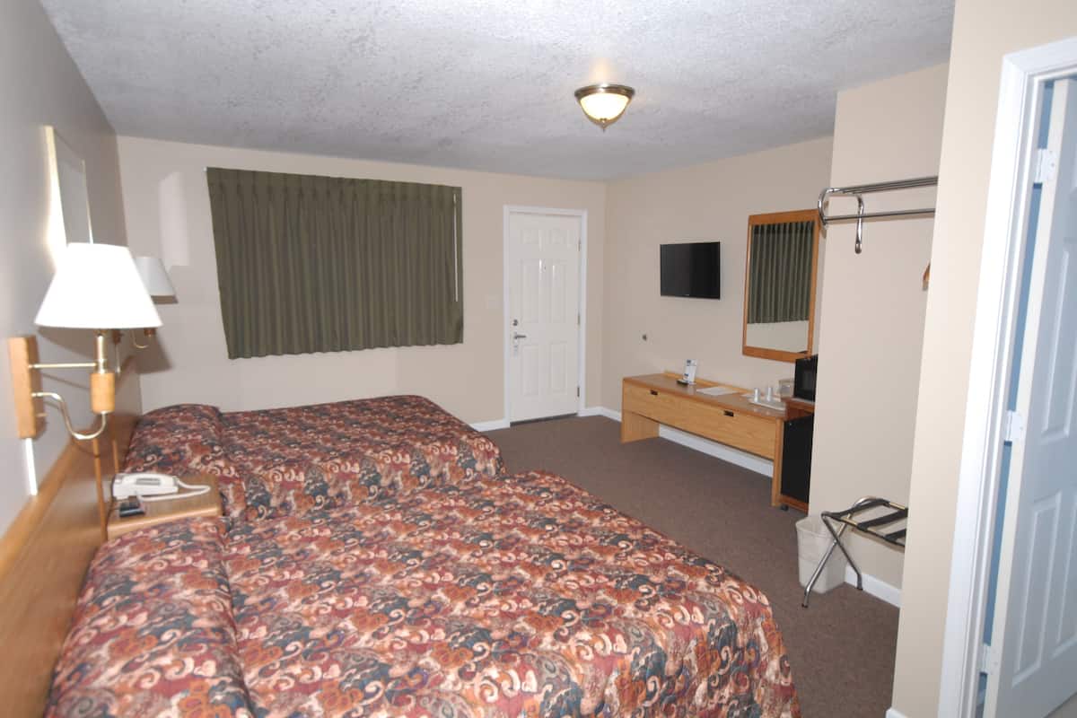 A hotel room with a bed, a desk, a chair, a TV, and a bathroom.