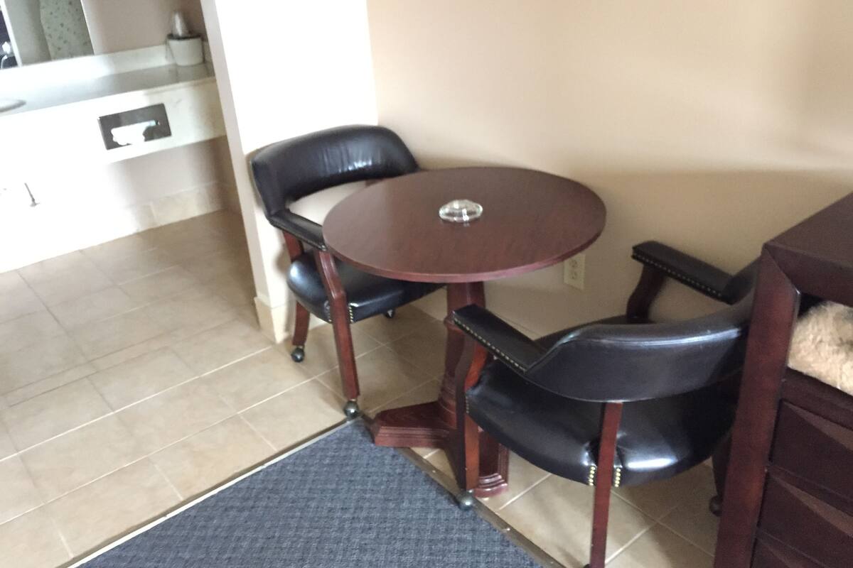 A small dining area with a round table and two chairs, a small rug, and a cabinet.