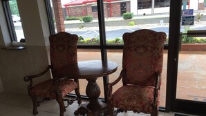 Un comedor con una mesa redonda y dos sillas ricamente decoradas con tapicería floral.