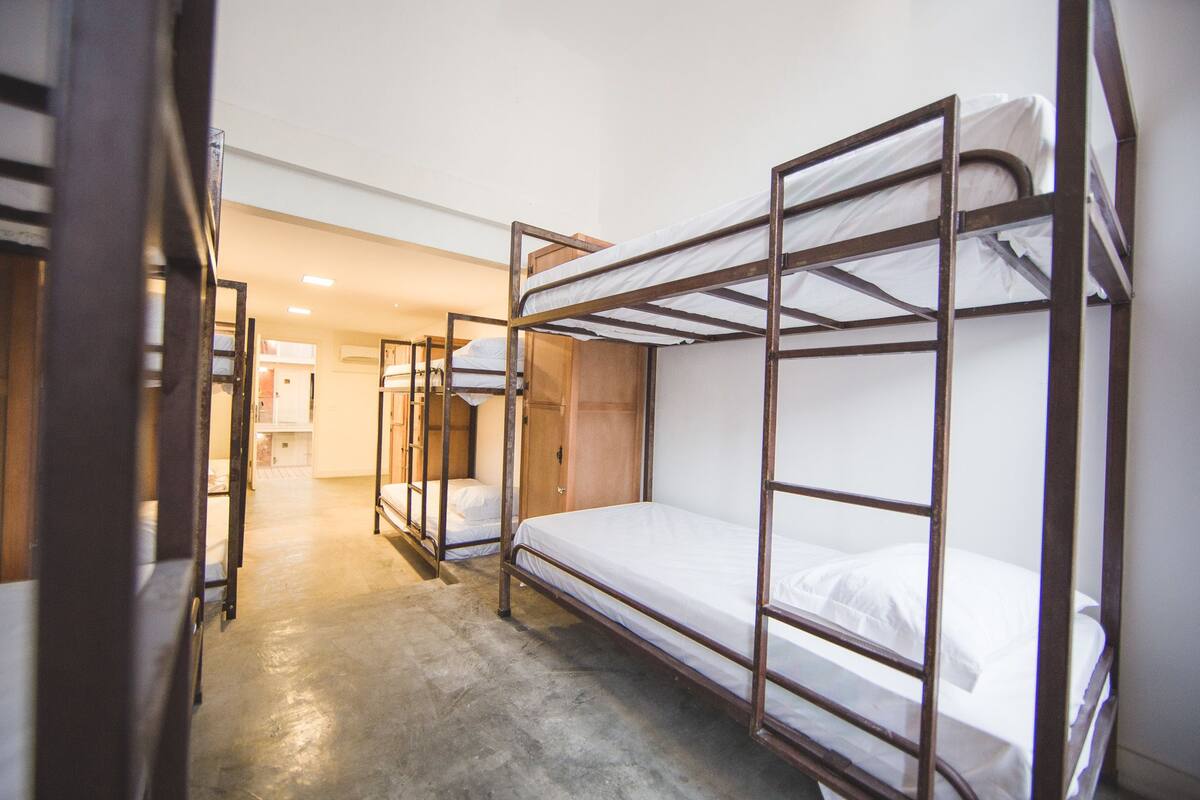 A dormitory room with bunk beds, wooden doors, and a concrete floor.