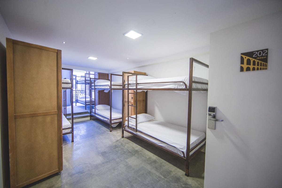 A room with bunk beds, a wardrobe, and a door with a number sign.