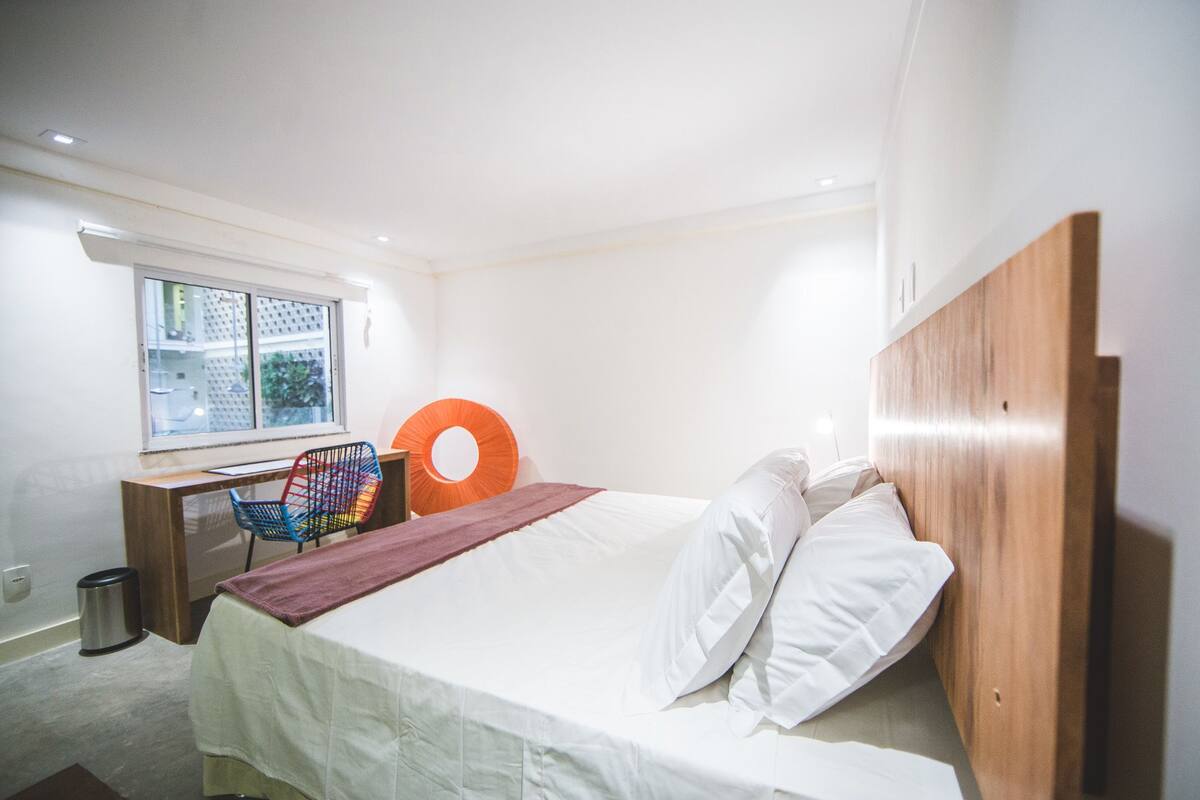 A bedroom with a bed, a desk, and a chair.