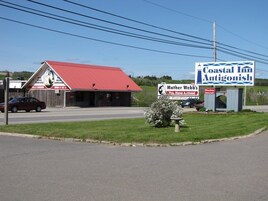 A Coastal Inn Antigonish signboard with a red-roofed building in the background.