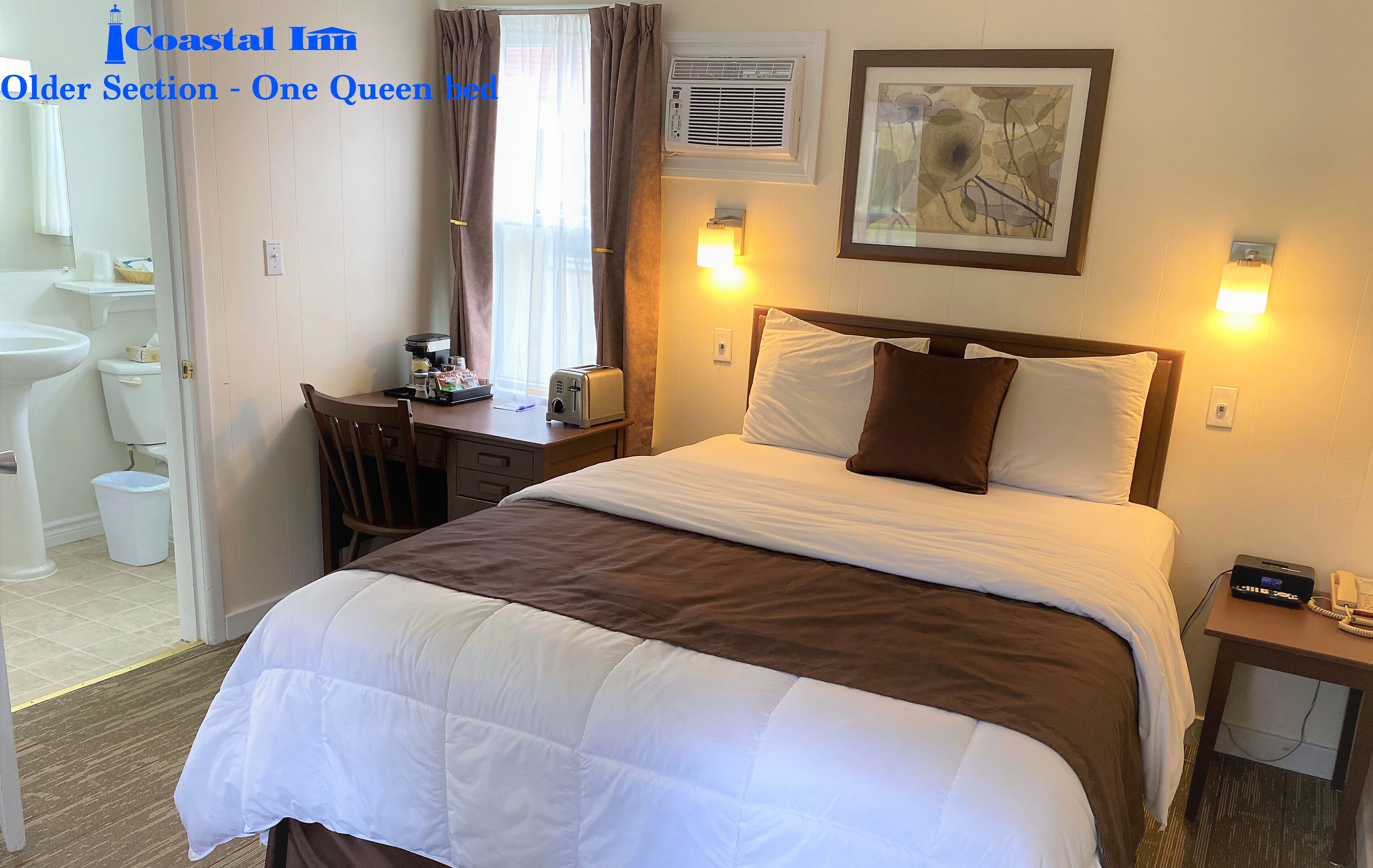 A hotel room with a bed, bedside table, lamp, and a window with curtains.