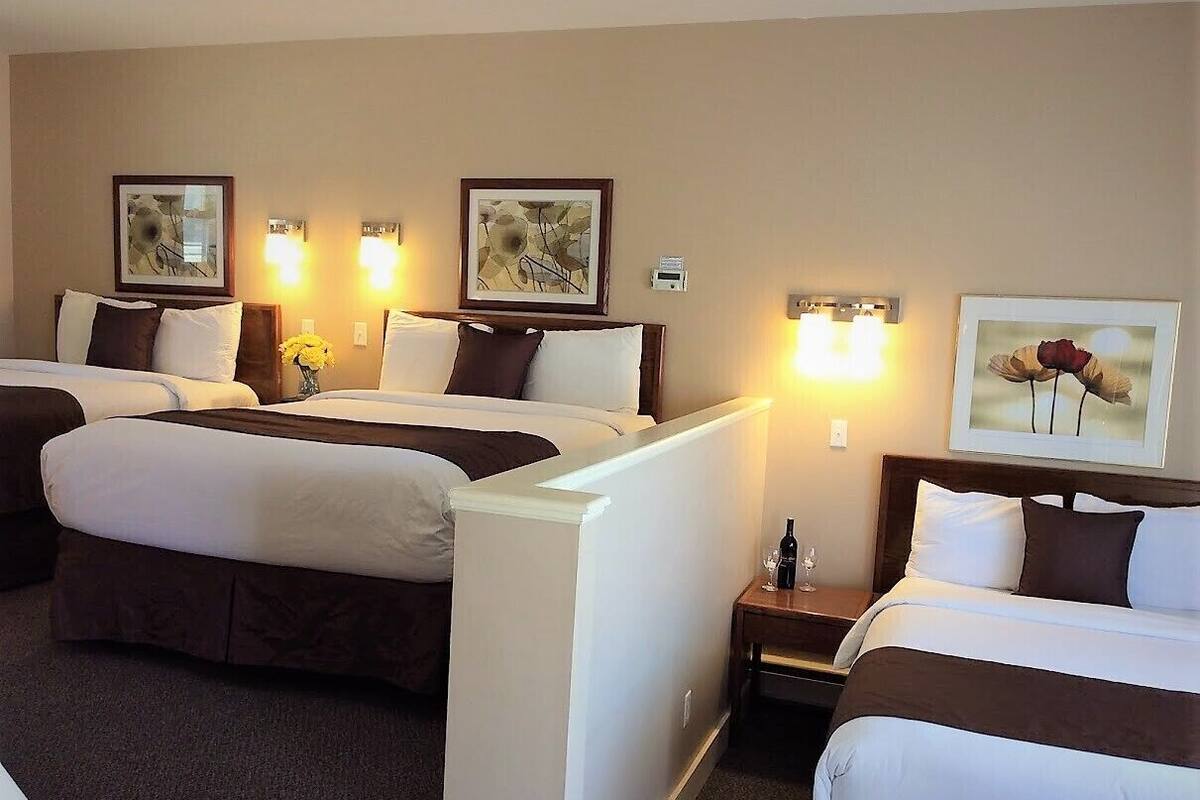A hotel room with two beds, a small table, and wall-mounted lamps.