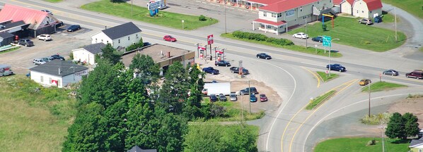 An aerial view of a commercial area with a gas station, a church, and a building with a red roof. - Coastal Inn Antigonish (Lower South River)