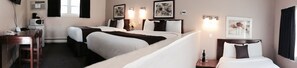 A hotel room with two single beds, a desk with a telephone and a coffee maker, and artwork on the walls. - Coastal Inn Antigonish (Lower South River)