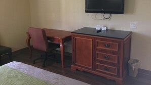 A hotel room with a wooden desk, a chair, a television mounted on the wall, and a trash can. - Red Carpet Inn New Brunswick (New Brunswick)