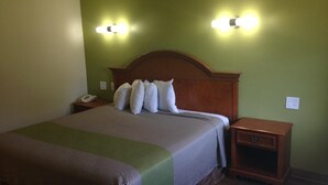 A hotel room with a bed, two bedside tables, a nightstand, and two wall-mounted light fixtures. - Red Carpet Inn New Brunswick (New Brunswick)