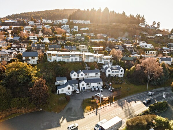 A residential area with houses on a hillside, a parking lot, and a road with vehicles.