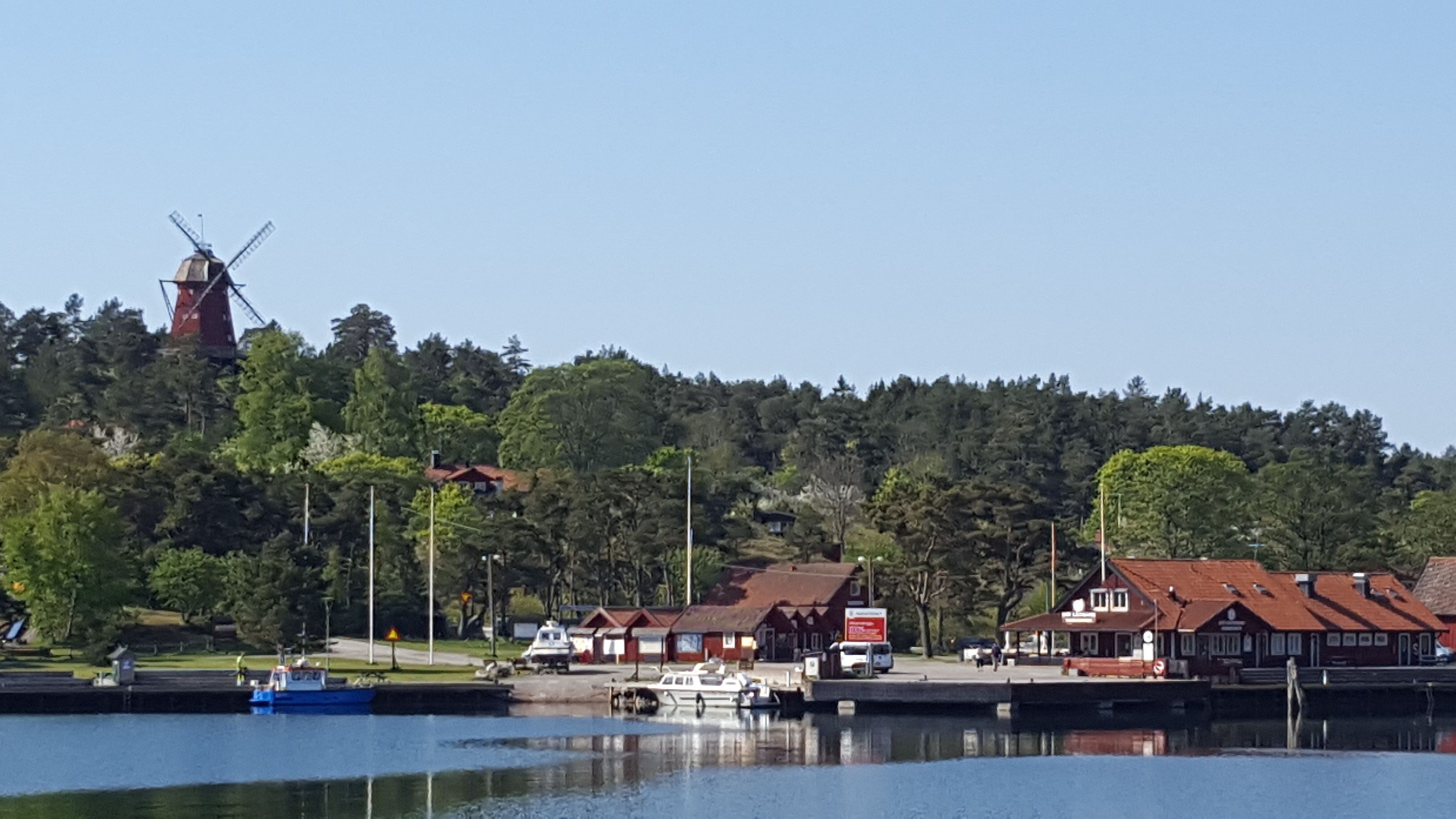 A lakeside town with a windmill, boats, and traditional houses.