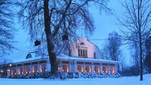 A snow-covered building with a large central window and a sign reading "Hotel Vardhus". - Utö Värdshus (Uto)