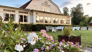 A building with a sign reading "utó várdshus" and a garden with benches and flowers. - Utö Värdshus (Uto)