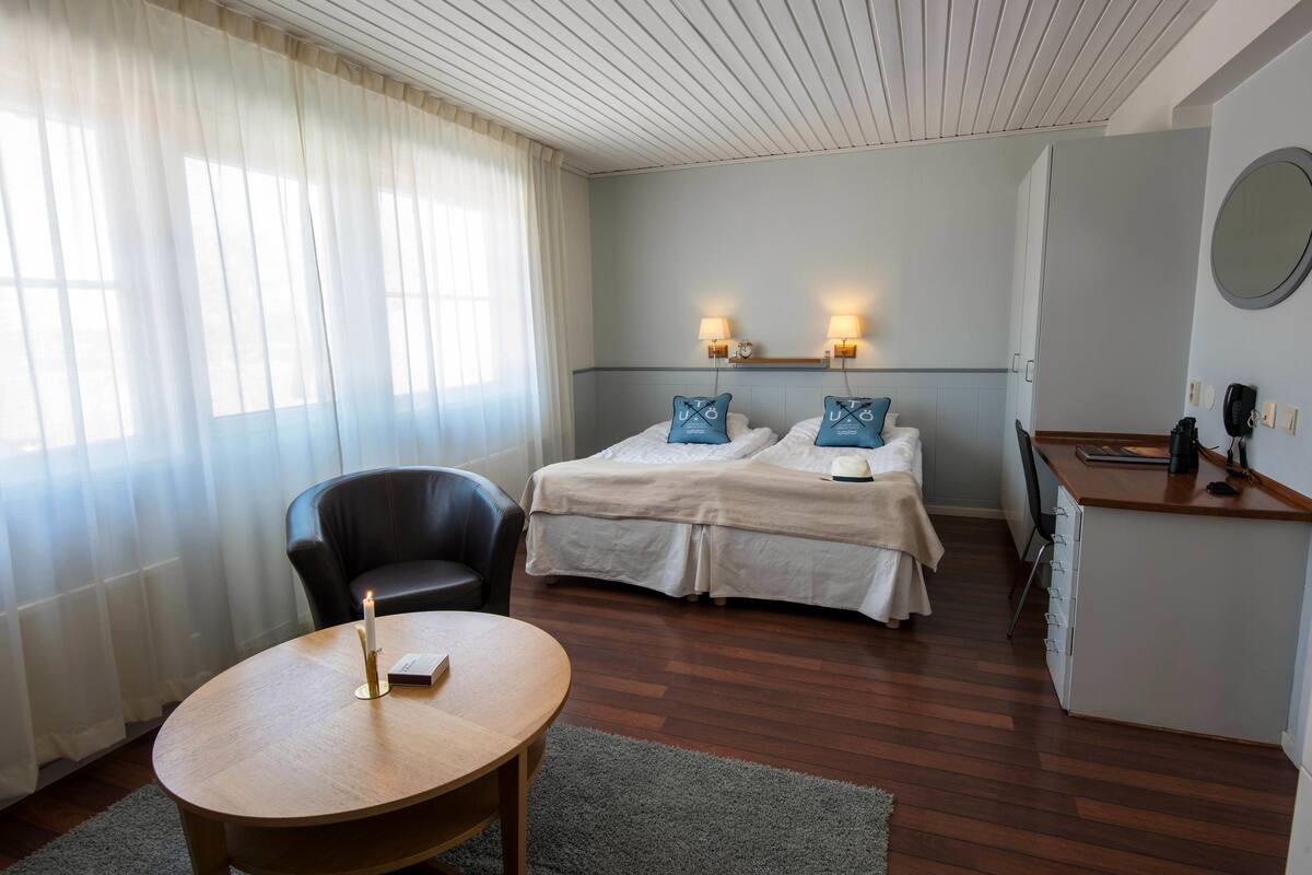 A hotel room with a bed, bedside tables, a desk, a chair, and a round table.