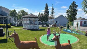 A playground with two deer statues, a swing set, and a gazebo.