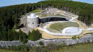 A modern building with a circular tower and a curved driveway.
