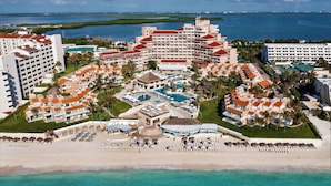 A resort with multiple buildings, a central pool area, and a beach.