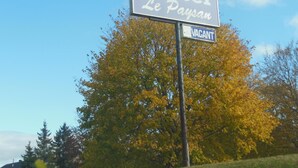Un letrero de motel con la leyenda 'Le Paysan' y una señal que indica 'VACANTE' debajo.