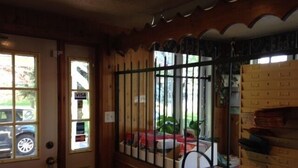 Una habitación con puerta de madera, ventana con reja de metal y vista a un coche estacionado afuera.