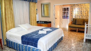 A bedroom with a bed, a nightstand, a chair, and a bathroom with a sink and mirror.