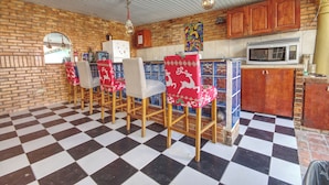 A kitchen with checkered flooring, wooden chairs, a microwave, and a brick wall.
