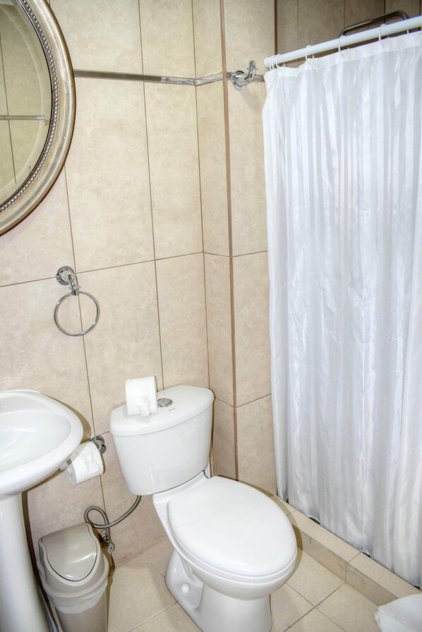 Un baño con inodoro, lavamanos y cortina de ducha.
