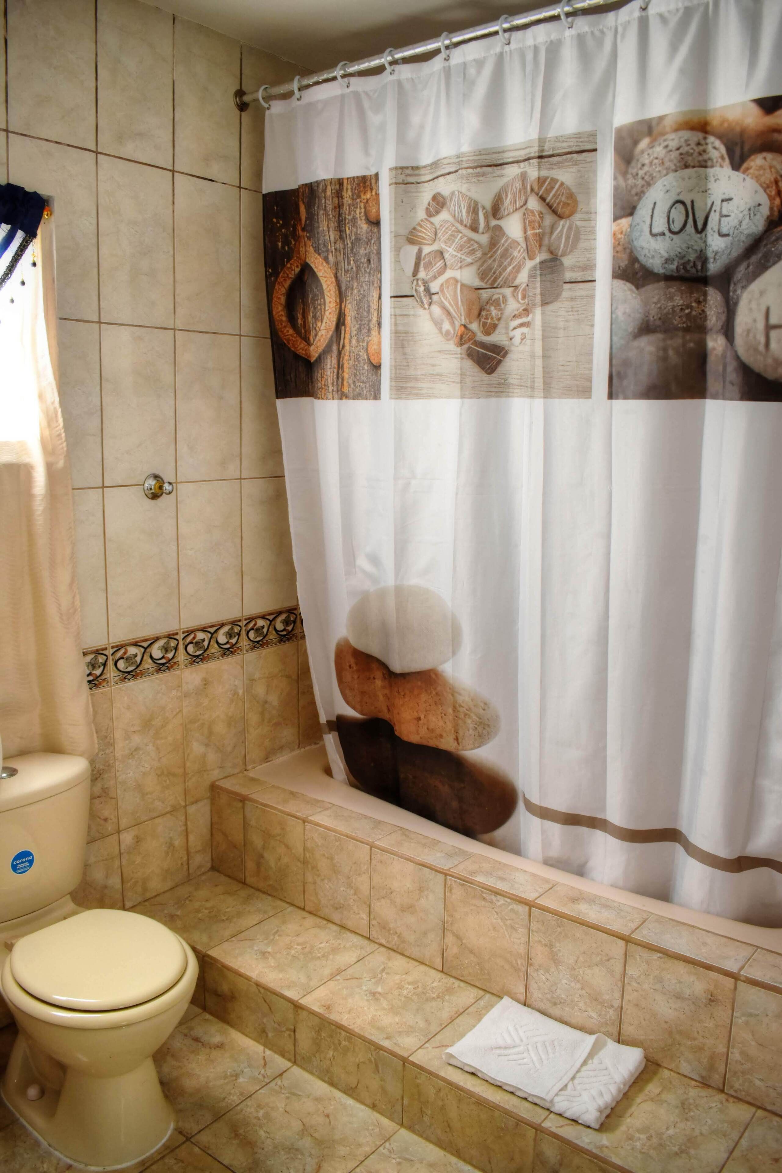 A bathroom with a shower curtain featuring a heart design, a toilet, and a bathtub.