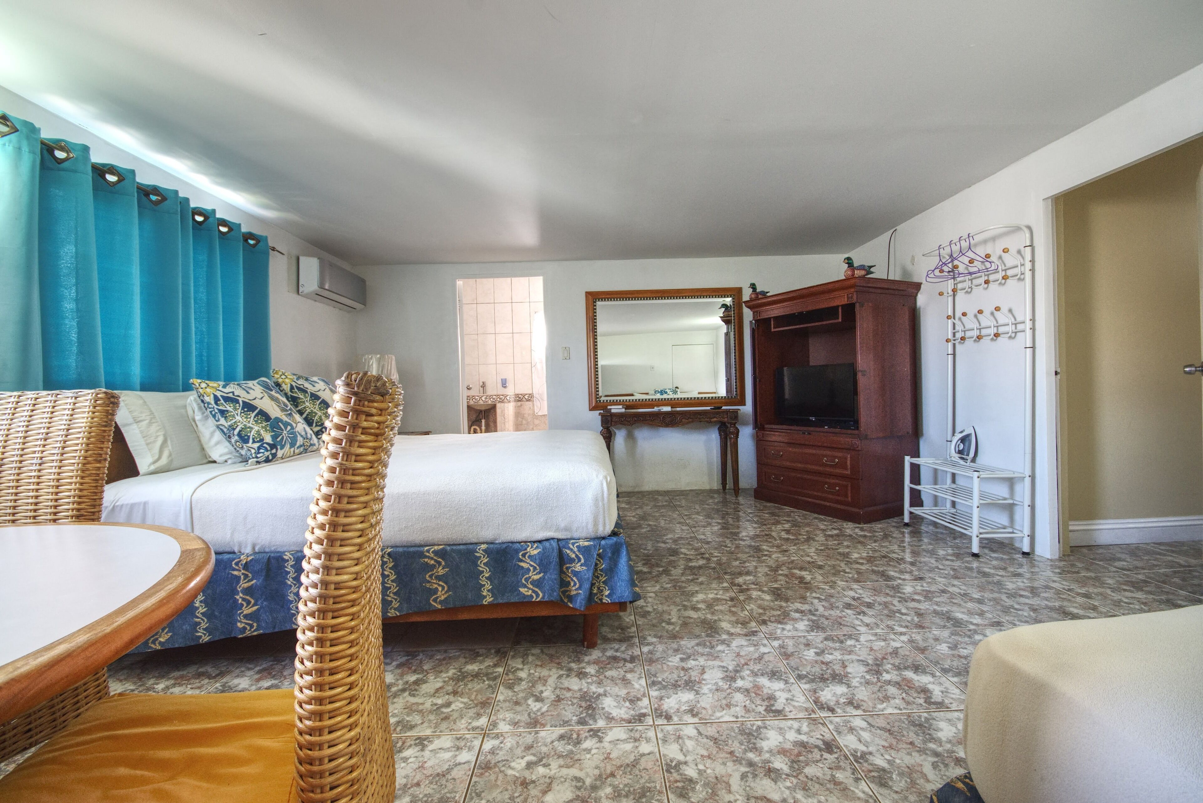 A bedroom with a bed, a television, a dresser, and a mirror.