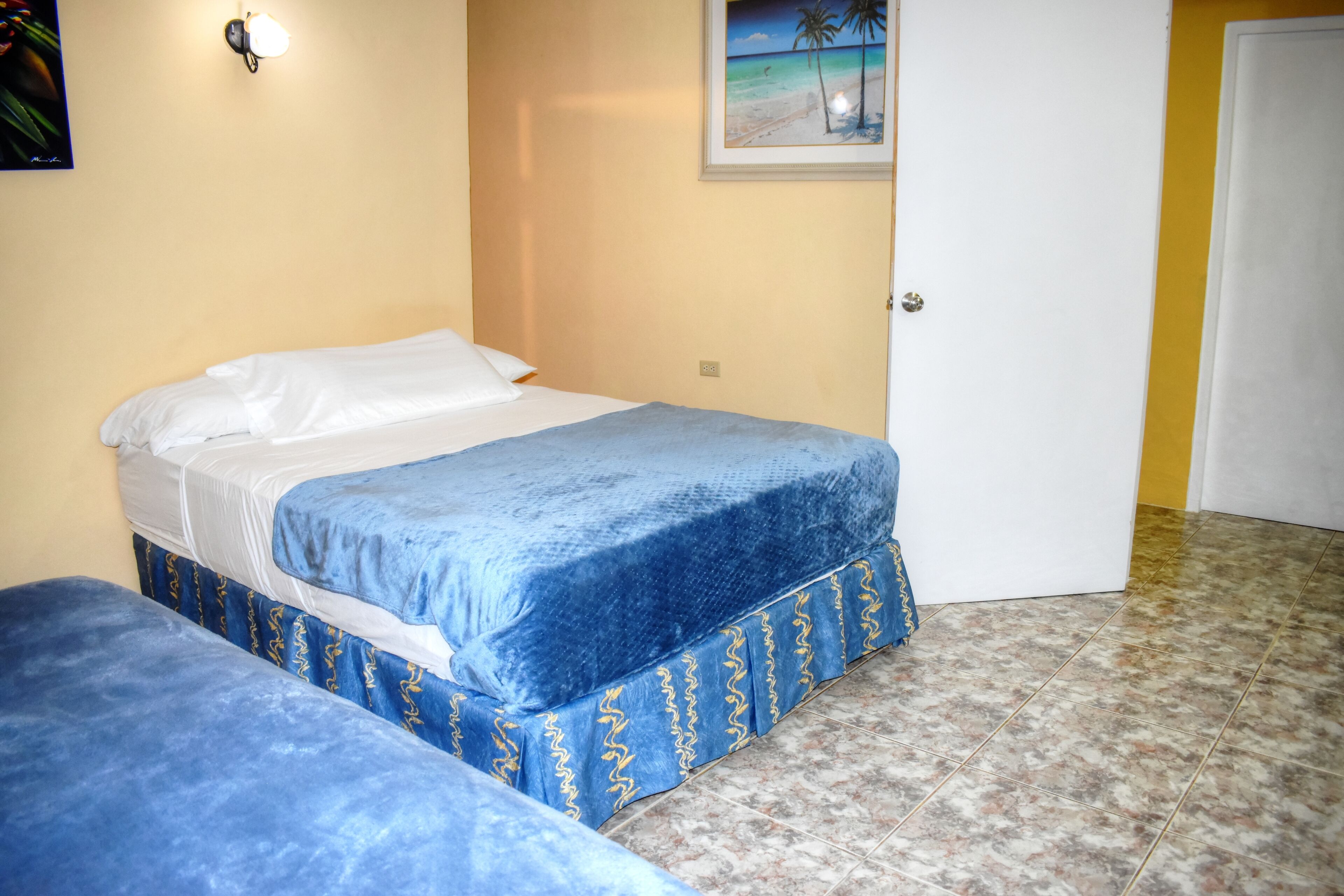 Ein Zimmer mit zwei Betten, einem Meeresblick-Gemälde und einer Tür.