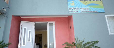 A building with a sign for 'Sandra Tours' advertising Aruba Island Tours, Palm Beach Retreat, and Palm Beach 504.