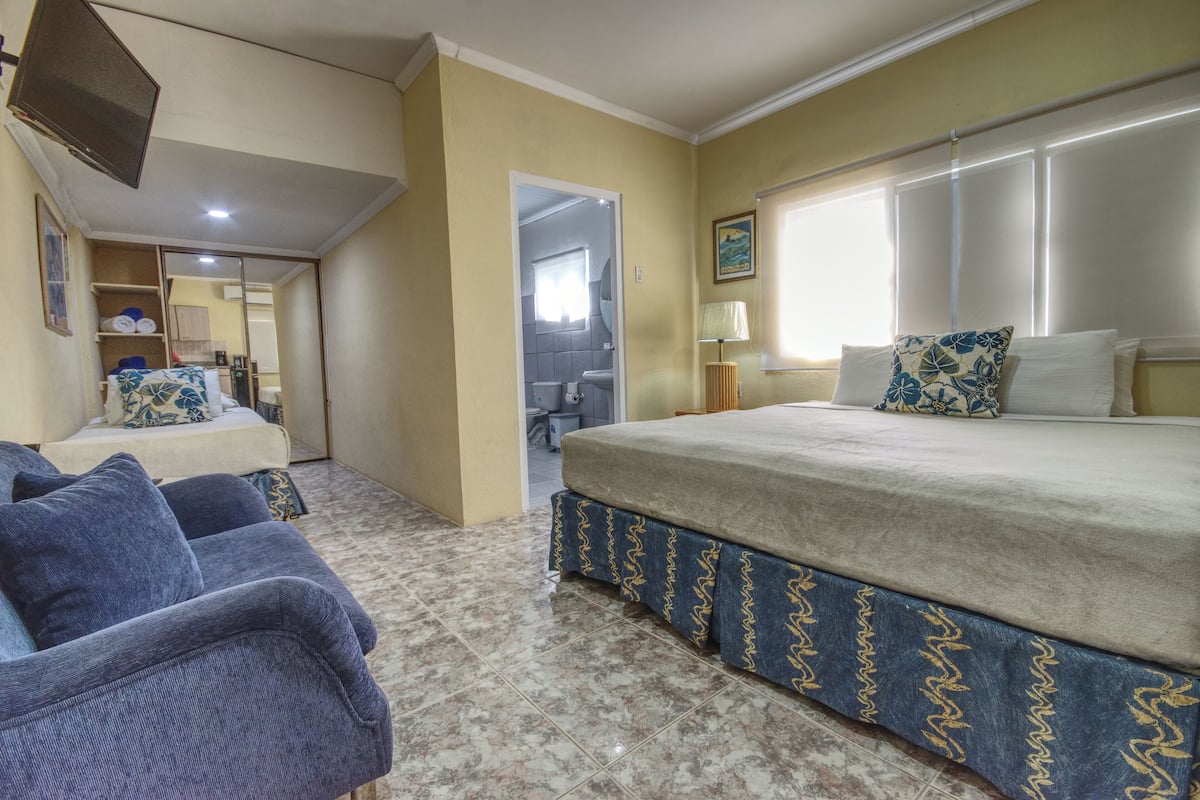 A bedroom with a bed, a sofa, and a bathroom visible through an open door.