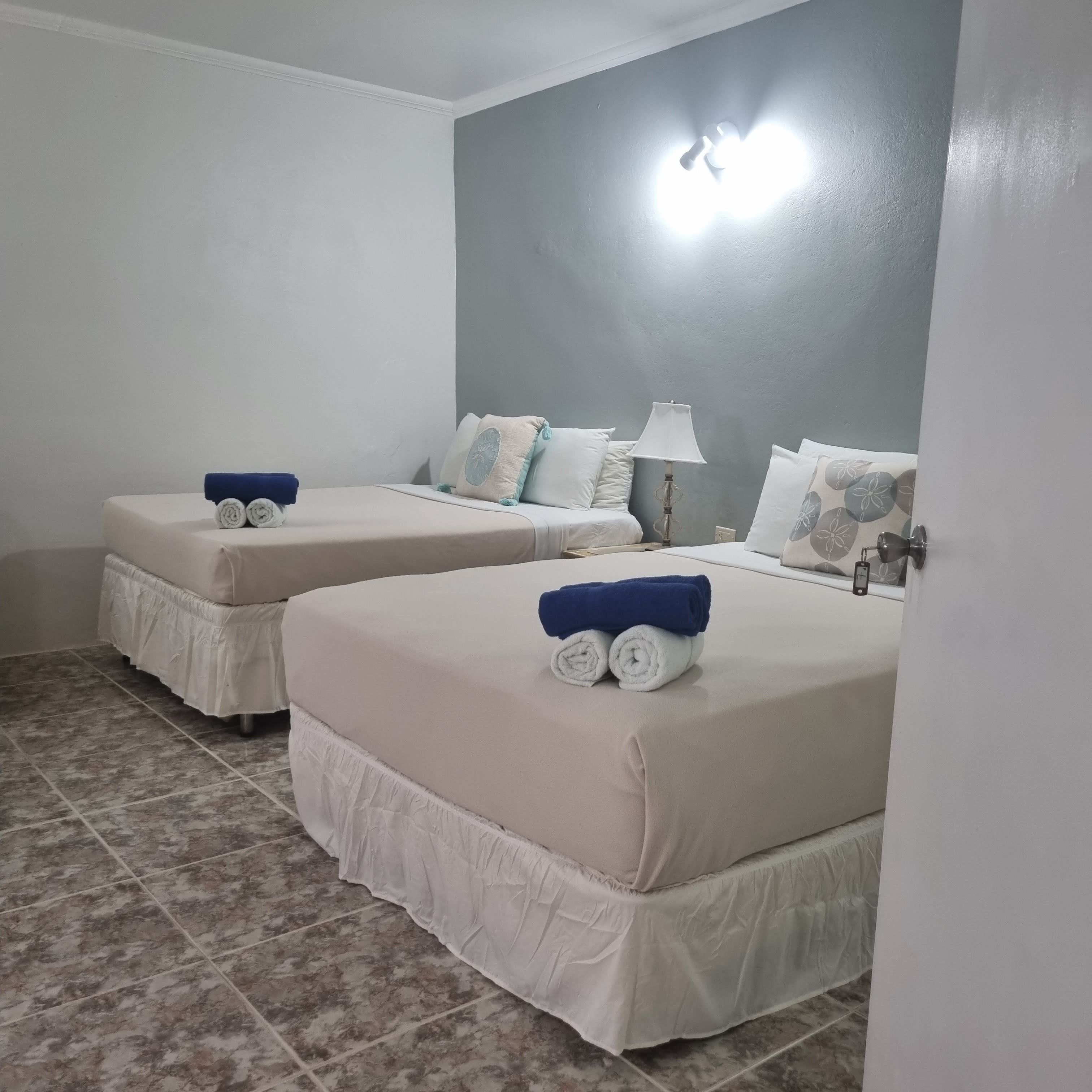 Een hotelkamer met twee bedden, elk met een witte matras en een blauwe handdoek.