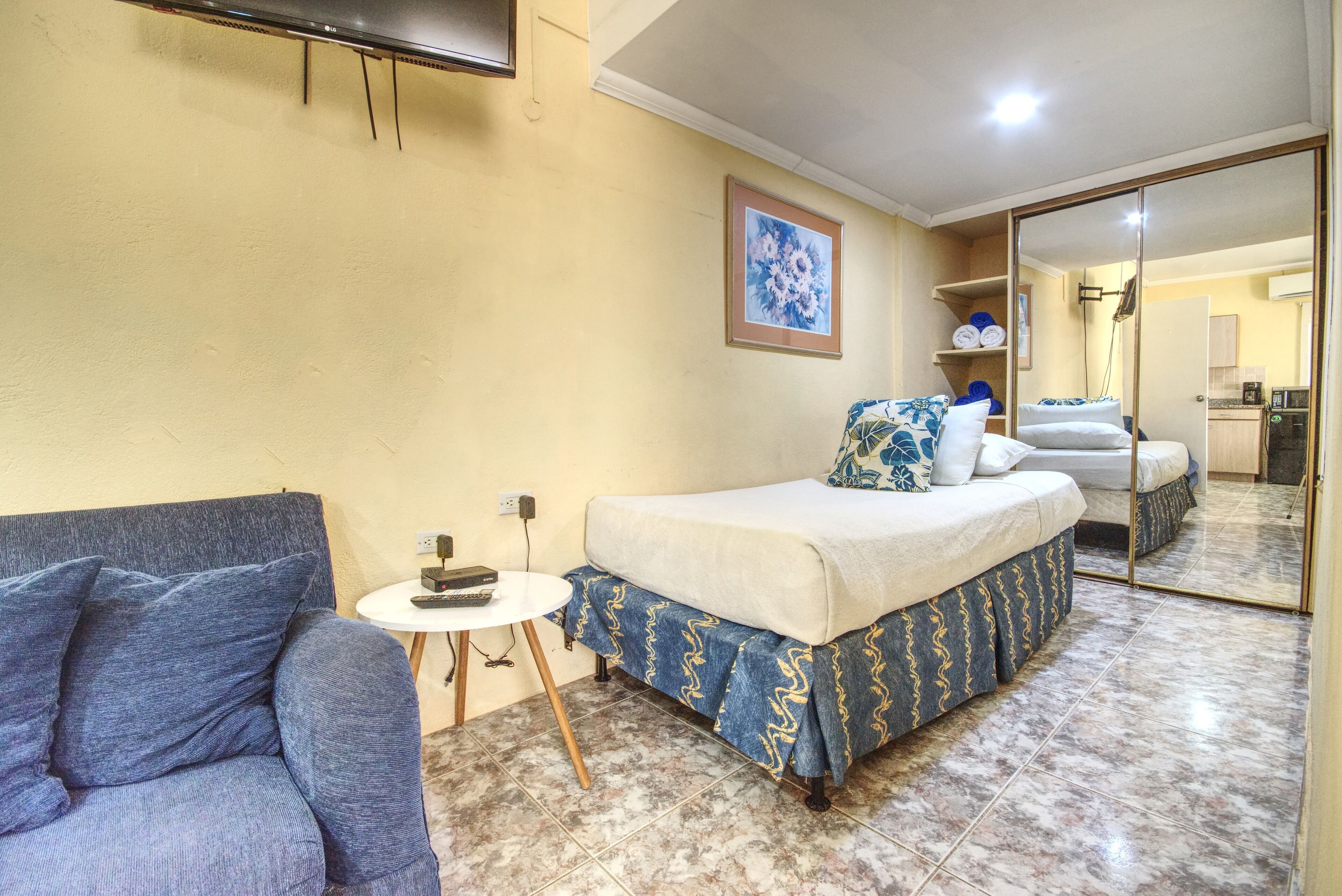 Un dormitorio con una cama, un sofá, una mesita y un espejo.